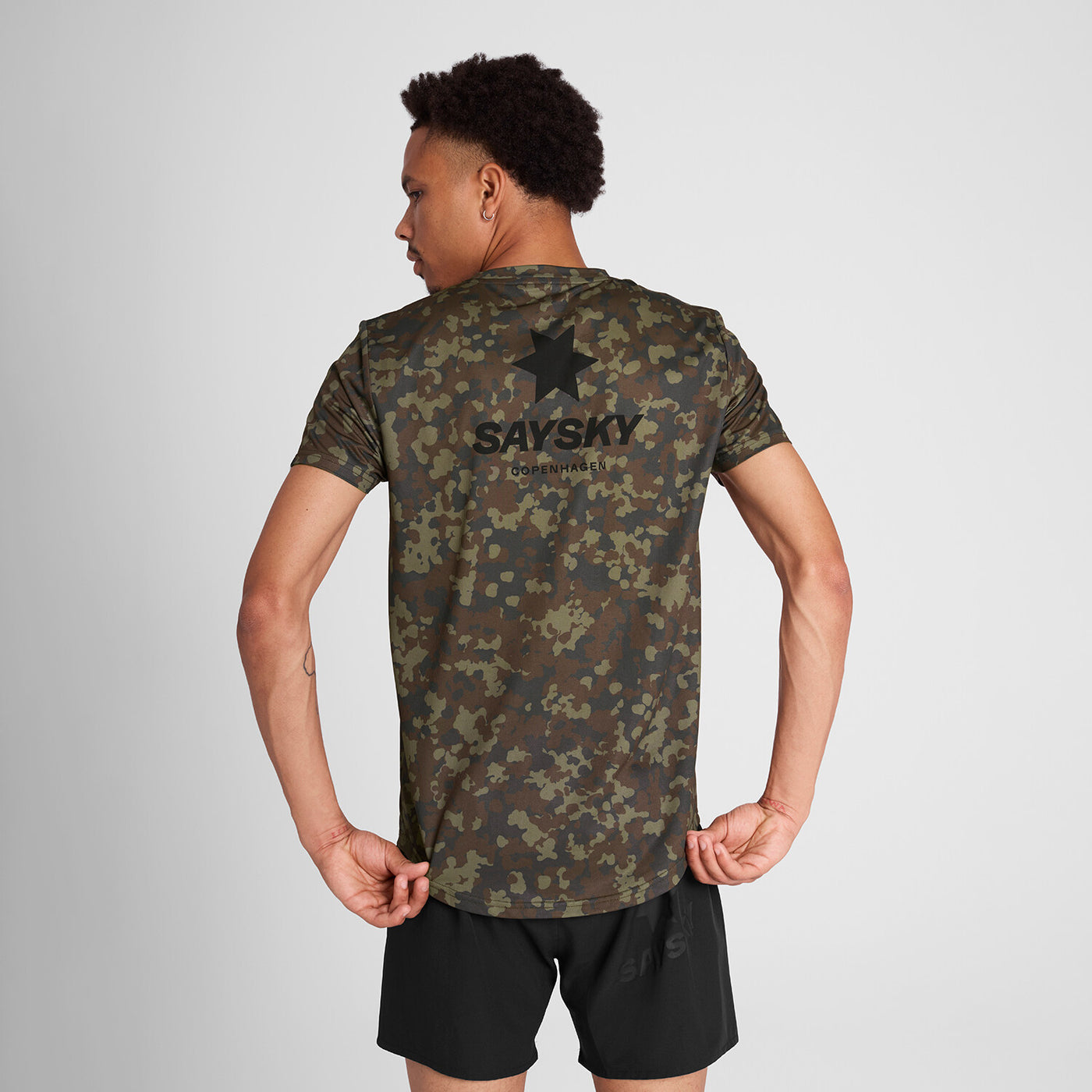 man wearing saysky camo combat tshirt, showing back with logo and star on the back