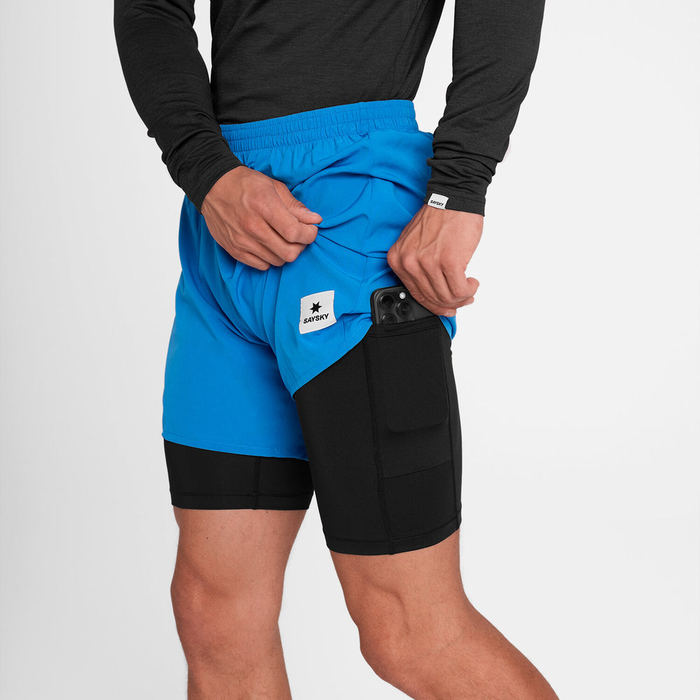 man taking out phone from thigh pocket of blue saysky 2 in 1 run short with black inner and logo
