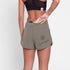 woman putting gel into the zip pocket at the back of the saysky pace 3 inch short for women in taupe colour