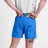 man wearing saysky pace 5 inch run shorts in blue colour with logo printed at front, putting gel into zip pocket