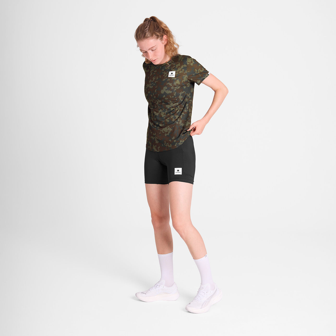 saysky lightweight running t-shirt for women, breathable and quick dry material,  brown and green camouflage colour, woman wearing saysky t-shirt with black shorts on a white background