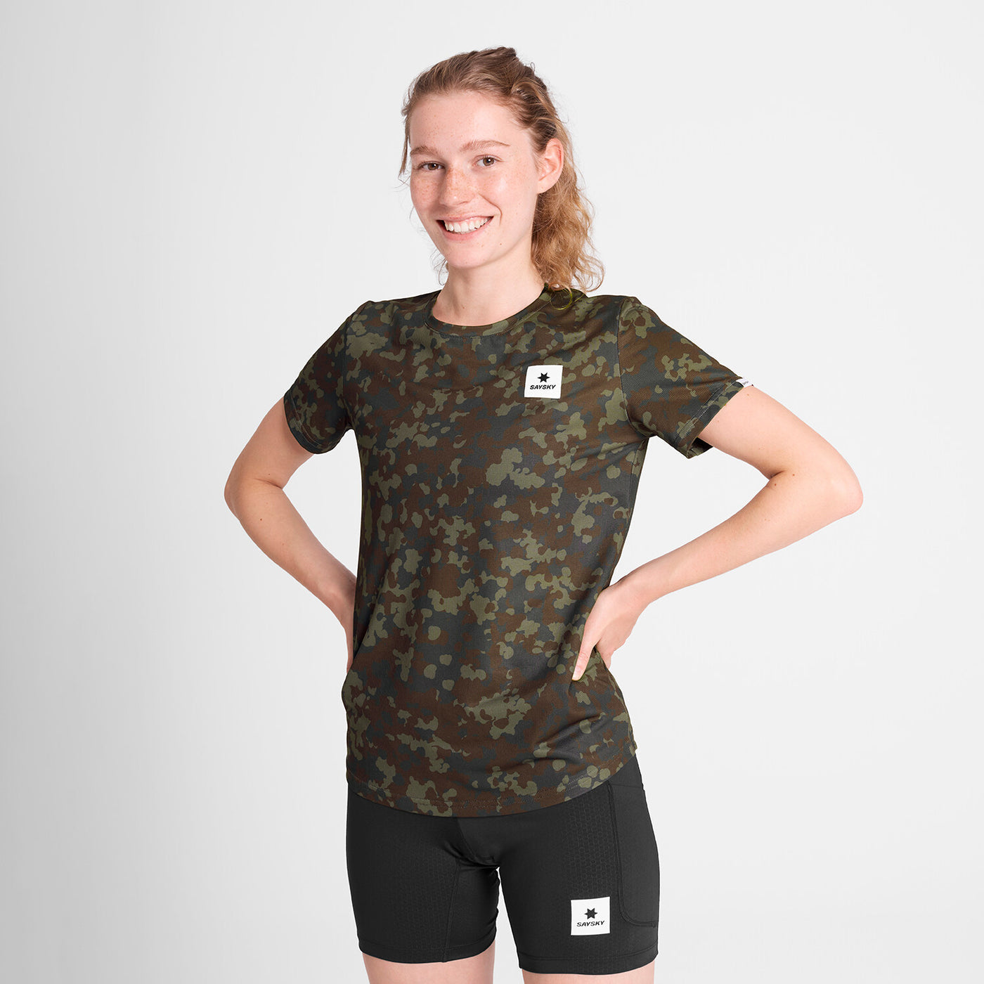 saysky lightweight running t-shirt for women, breathable and quick dry material,  brown and green camouflage colour, woman wearing saysky t-shirt with black shorts on a white background