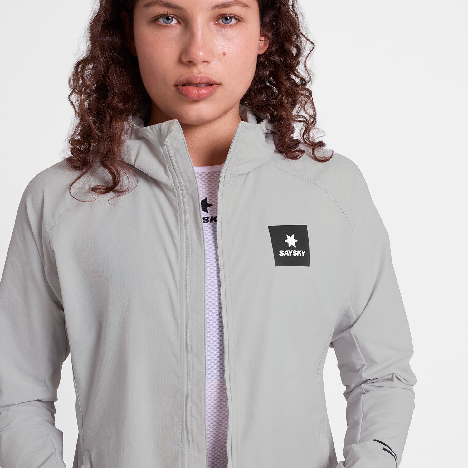 saysky womens pace flex hooded jacket sleeve, Wind-resistant, breathable jacket for running, light grey colour, woman wearing saysky grey jacket zip open