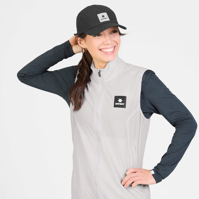 SAYSKY womens clean pace flex vest, lightweight, windproof zip-up running vest for women, grey colour with black SAYSKY logo, women wearing vest with black longsleeve and cap on a white background
