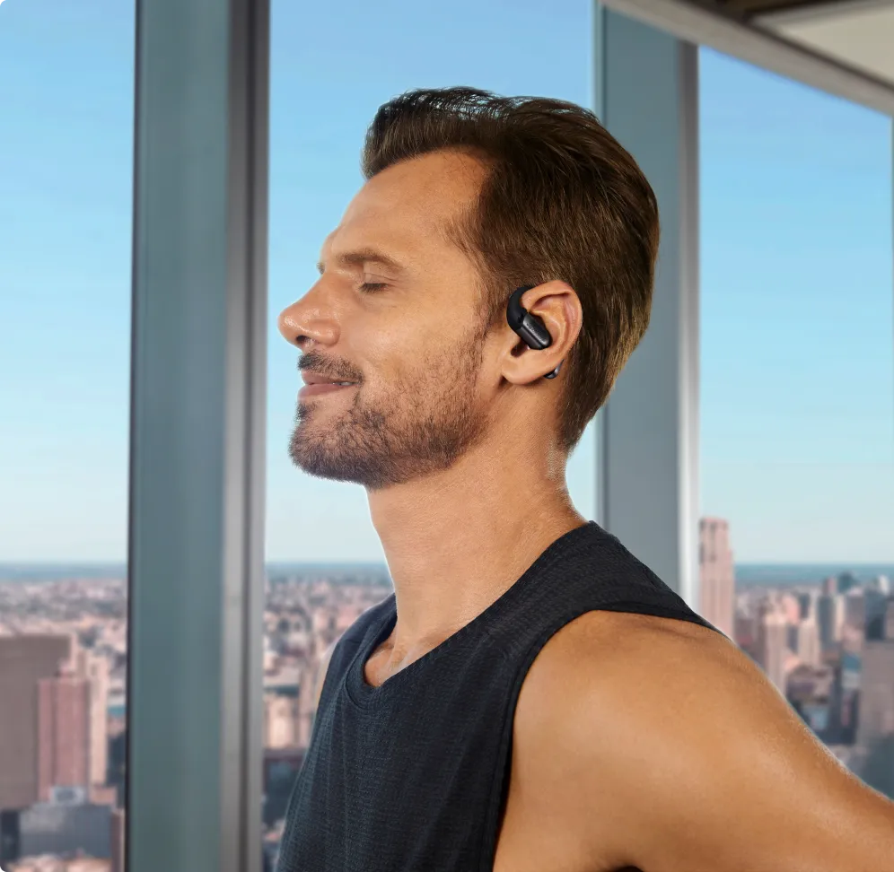 shokz openfit pro, wireless noise bone noise conducting earbuds, black colour, man wearing headphones with city in background