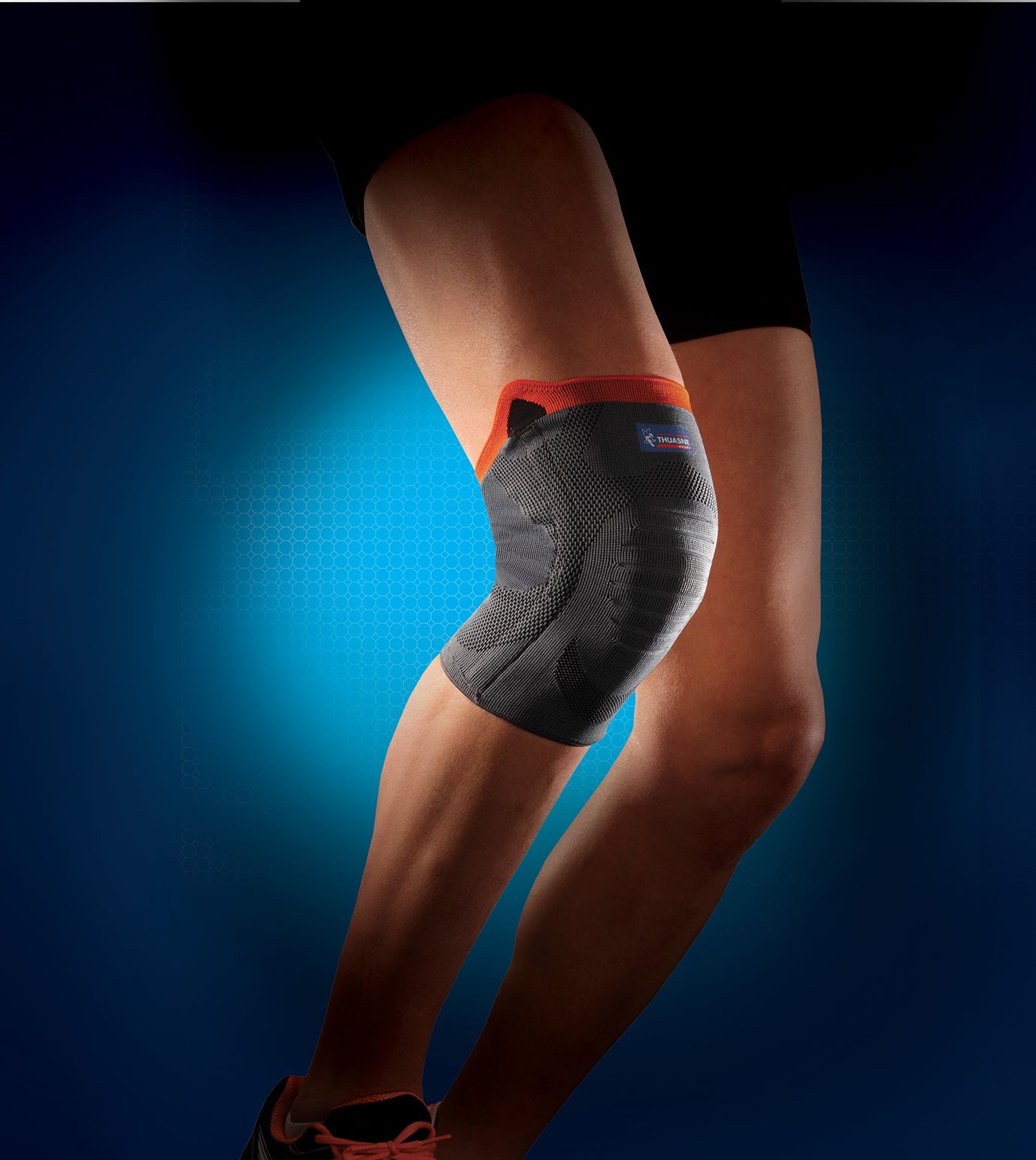 Person wearing Thuasne knee support for knee pain and/or swelling management, grey / orange colour