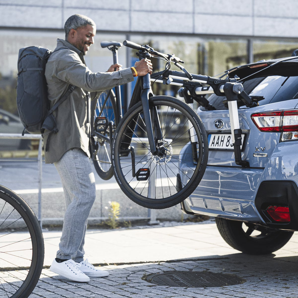thule outway hanging rack, man taking bike off rack that is mounted on blue suv
