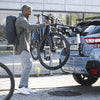 thule outway hanging rack, man taking bike off rack that is mounted on blue suv