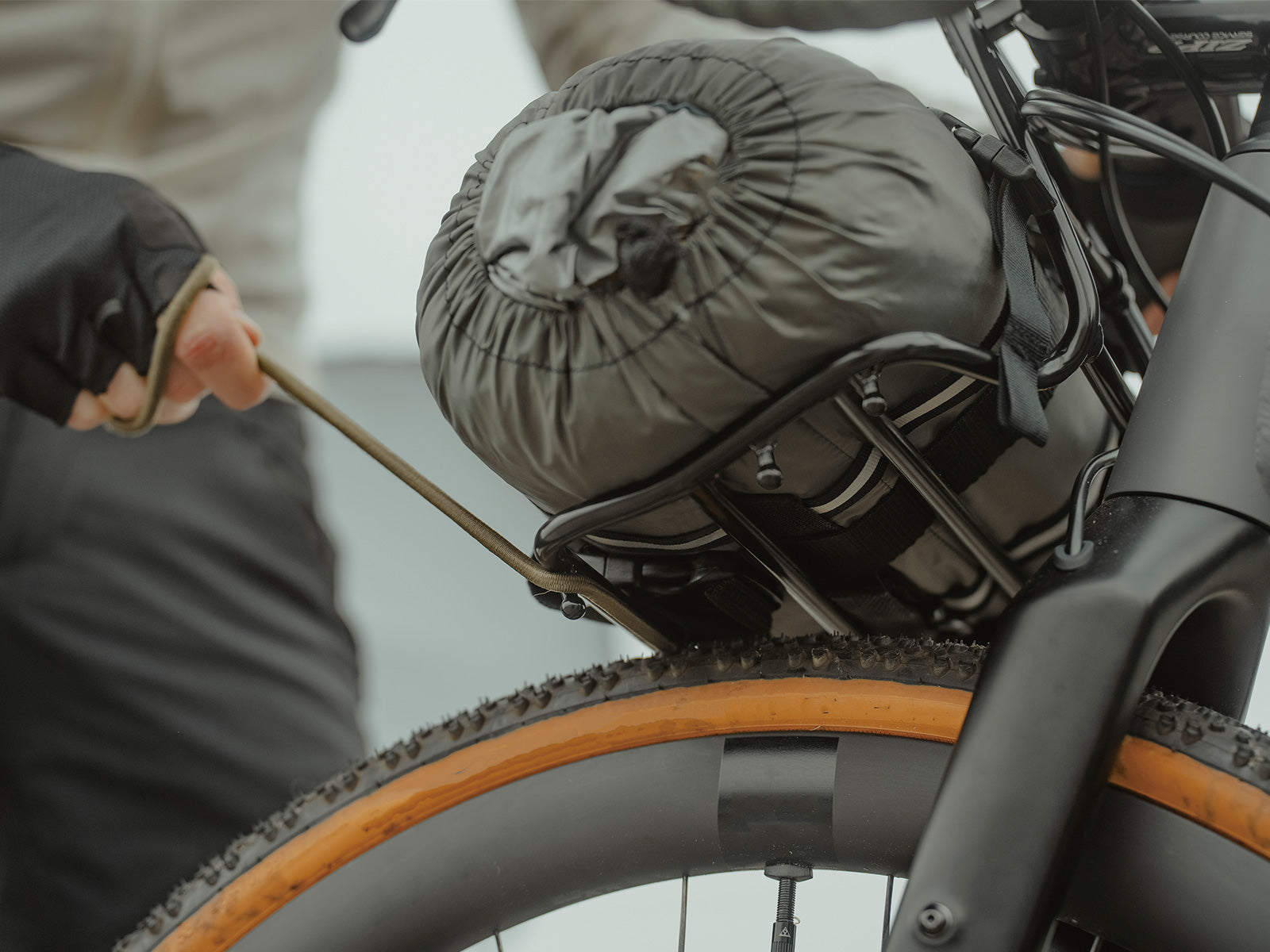 topeak argo elastic cord, stretch cord for holding down supplies when cycling, olive green cord with black hooks, cord on bike rack above tyre
